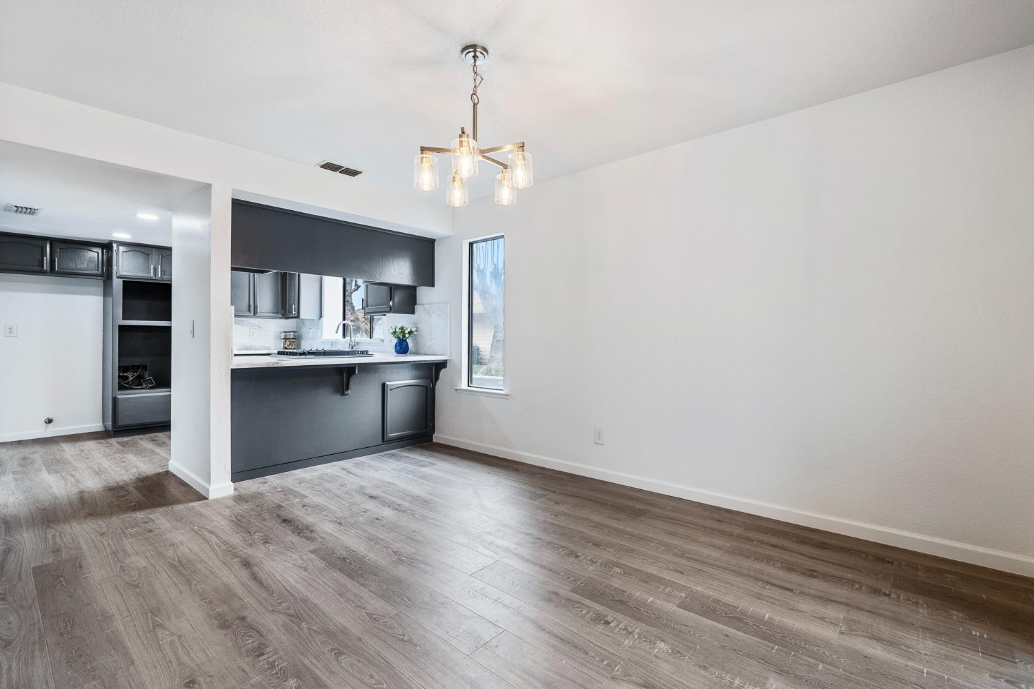929 Barnett Way Madera, CA 93637 - Photo 7 of 23 an empty room with wooden floor and kitchen view
