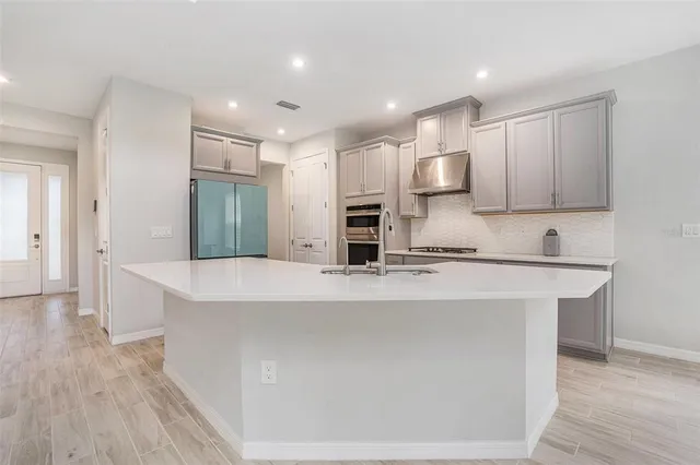 a large kitchen with stainless steel appliances a large counter top a stove and a refrigerator