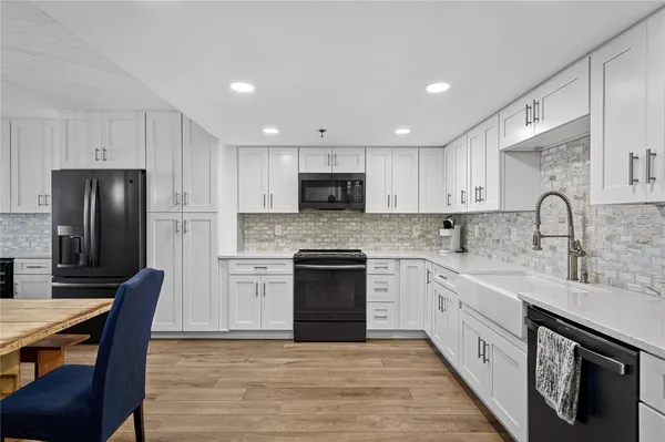 a kitchen with granite countertop white cabinets and stainless steel appliances