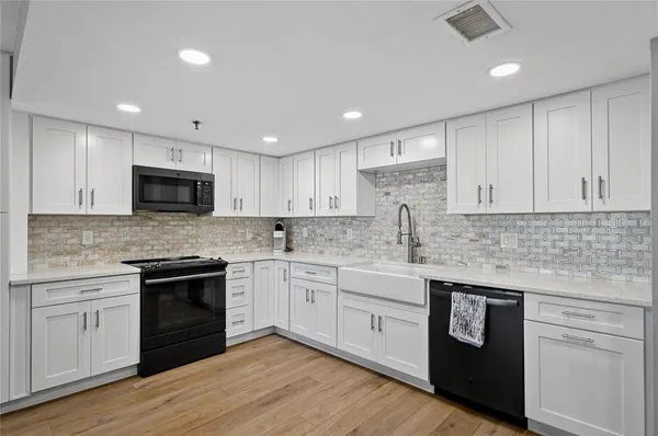 a kitchen with granite countertop white cabinets and stainless steel appliances