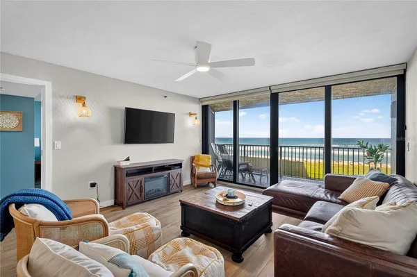 a living room with furniture floor to ceiling window hardwood floor and a flat screen tv