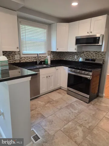 a kitchen with granite countertop white cabinets and a sink