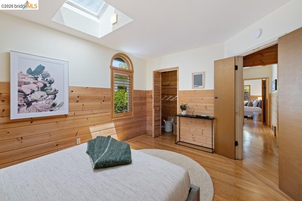 287 Purdue Avenue Kensington, CA 94708 - Photo 44 of 60 Bedroom featuring wood-finish flooring, a skylight, and partial wood-paneled walls
