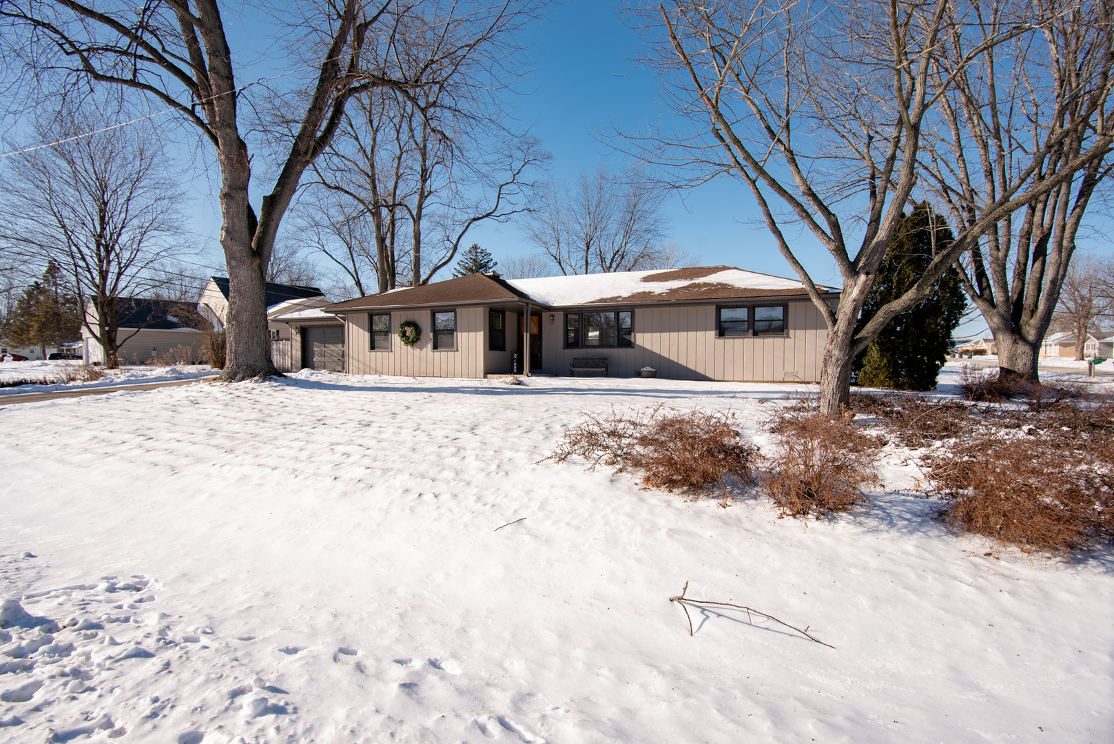 a front view of house with yard covered in snow