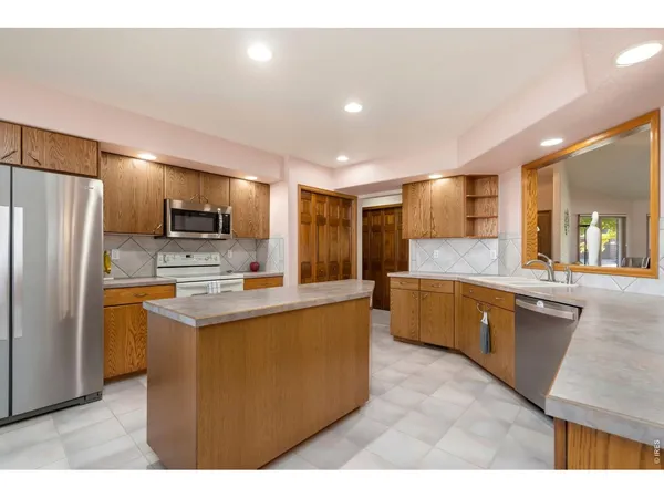 a large kitchen with kitchen island a large counter top stainless steel appliances and cabinets