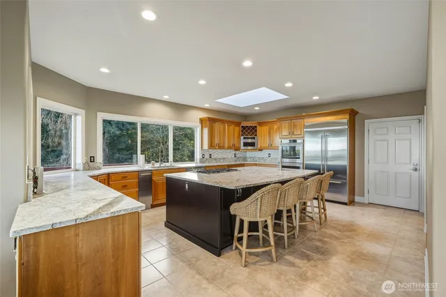 a dining hall with stainless steel appliances granite countertop a sink and a large window