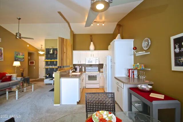 a kitchen with stainless steel appliances kitchen island granite countertop a refrigerator a stove a oven with white cabinets and couches