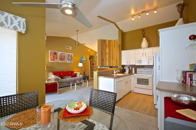 a kitchen with stainless steel appliances granite countertop a stove a sink dishwasher a dining table and chairs with wooden floor