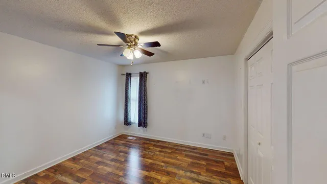 a view of an empty room with window and wooden floor
