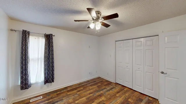 a view of an empty room with a window and wooden floor