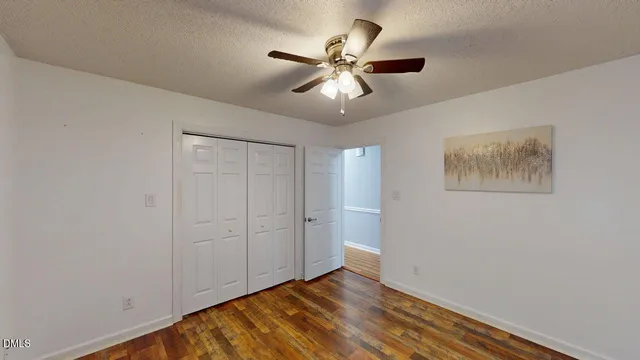 an empty room with wooden floor and a ceiling fan