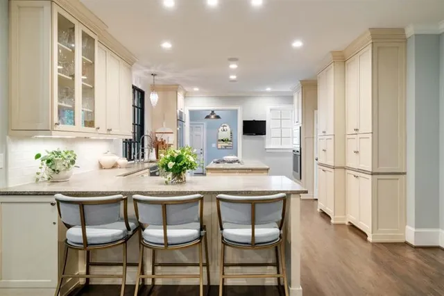 a large white kitchen with stainless steel appliances granite countertop a stove and a sink