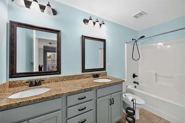 a bathroom with a granite countertop sink mirror toilet and bathtub
