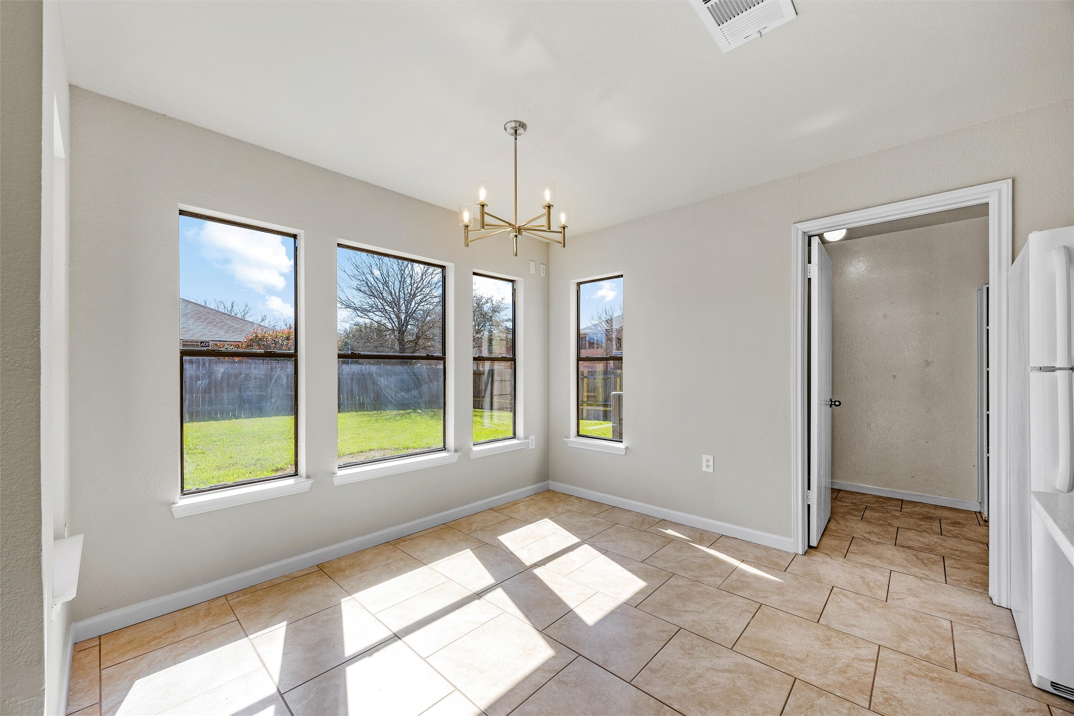 7541 Redrick Drive Austin, TX 78747 - Photo 21 of 40 Unfurnished dining area featuring light tile patterned flooring, visible vents, baseboards, and an inviting chandelier