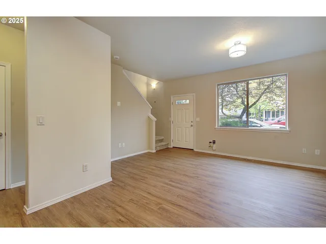 a view of an empty room with wooden floor and windows