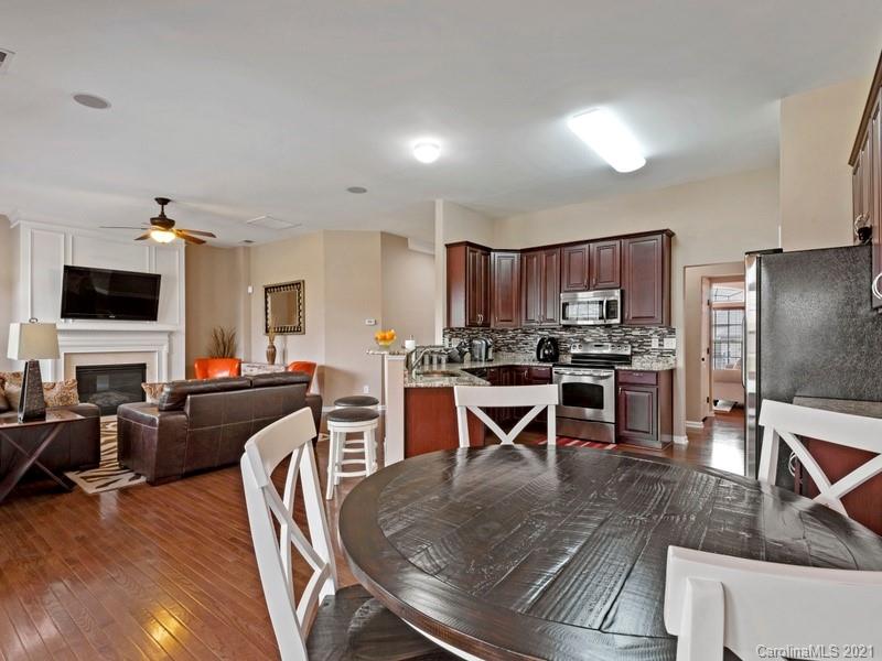 7726 Wiltshire Ridge Road Charlotte, NC 28269 - Photo 9 of 26 a kitchen with stainless steel appliances granite countertop a stove top oven a sink a dining table and chairs with wooden floor