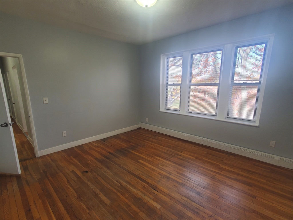10 Abbotsford Street, Unit 9 Boston, MA 02121 - Photo 7 of 14 an empty room with wooden floor and windows