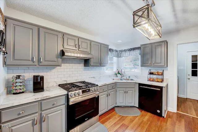 a kitchen with stainless steel appliances granite countertop a sink a stove and cabinets