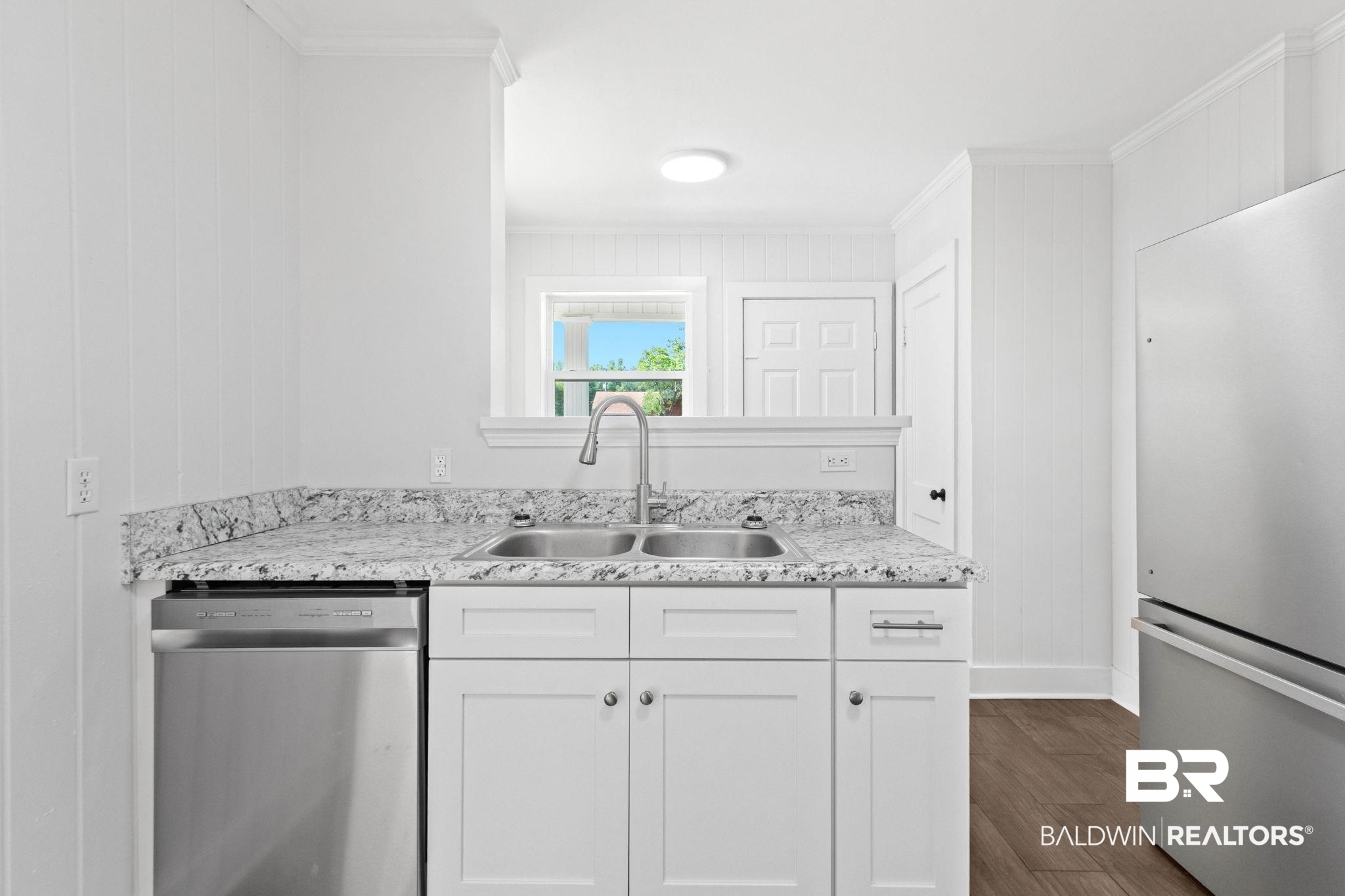 311 Cloverdale Road Atmore, AL 36502 - Photo 15 of 63 Kitchen featuring white shaker cabinetry, stainless steel dishwasher, double basin sink with gooseneck faucet, light-toned granite-style countertops, and paneling accents