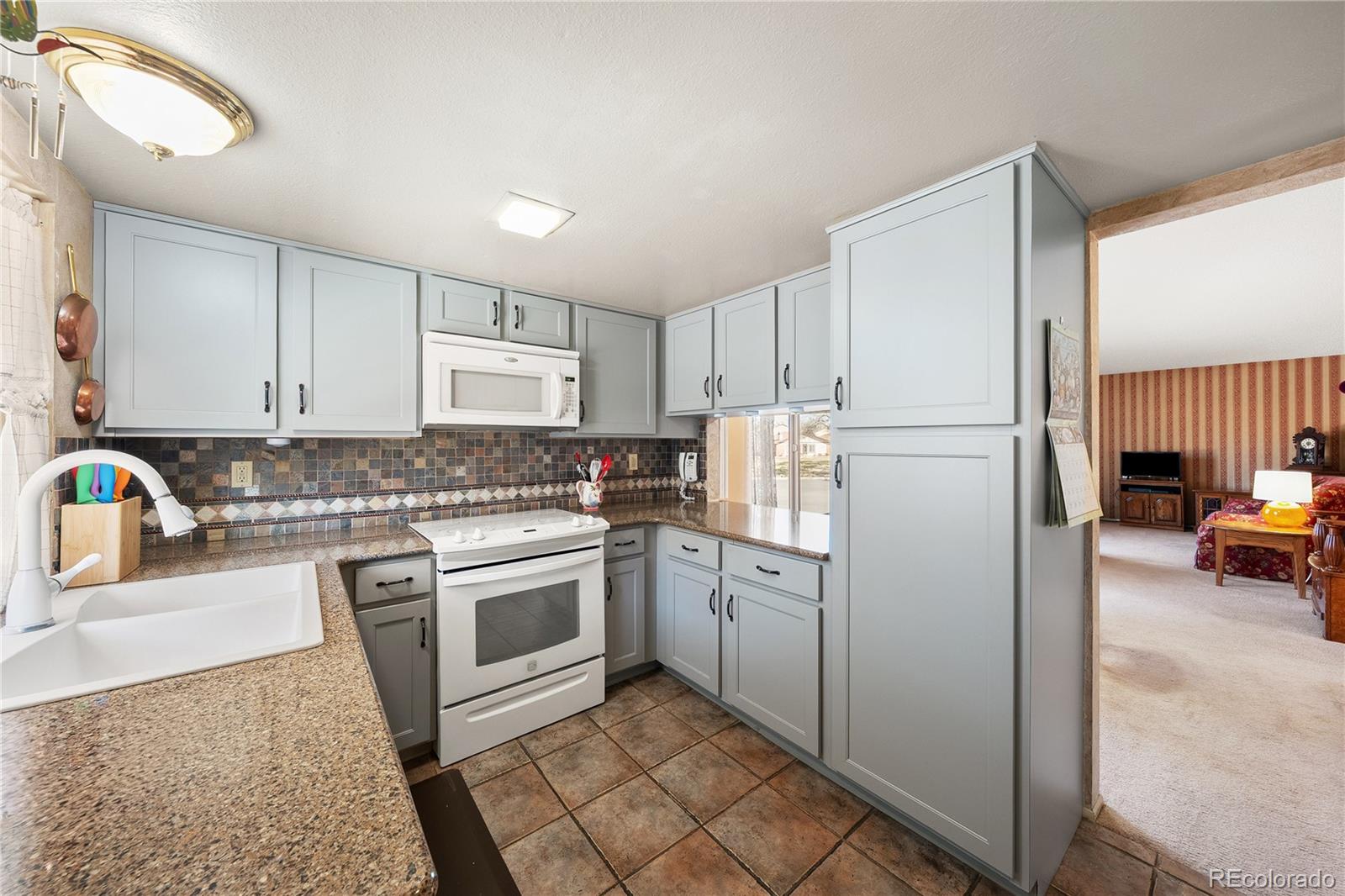 3657 South Laredo Street, Unit A Aurora, CO 80013 - Photo 12 of 26 a kitchen with a refrigerator sink and cabinets