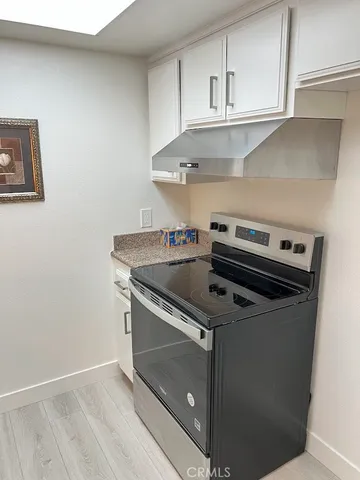 a room with wooden floor and stainless steel appliances