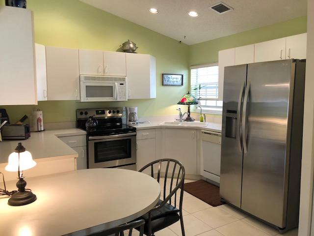 15290 Lake Wildflower Road Delray Beach, FL 33484 - Photo 10 of 22 a kitchen with a refrigerator a stove a sink a dining table and chairs