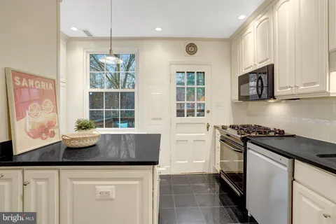 a kitchen with granite countertop a sink a stove and cabinets