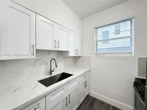 a kitchen with stainless steel appliances granite countertop white cabinets sink and window