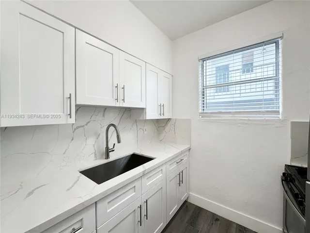 a kitchen with stainless steel appliances granite countertop white cabinets sink and window