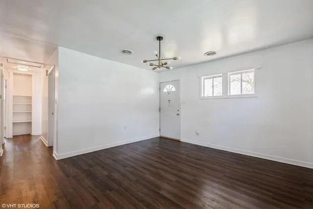 an empty room with wooden floor a ceiling fan and windows