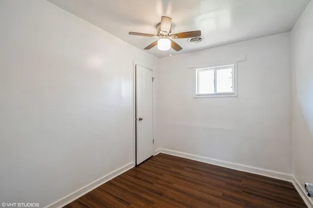 an empty room with wooden floor fan and windows