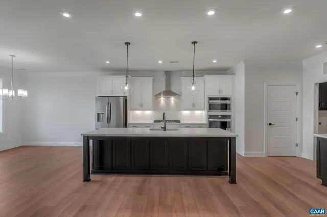 a kitchen with kitchen island stainless steel appliances a sink cabinets and wooden floor