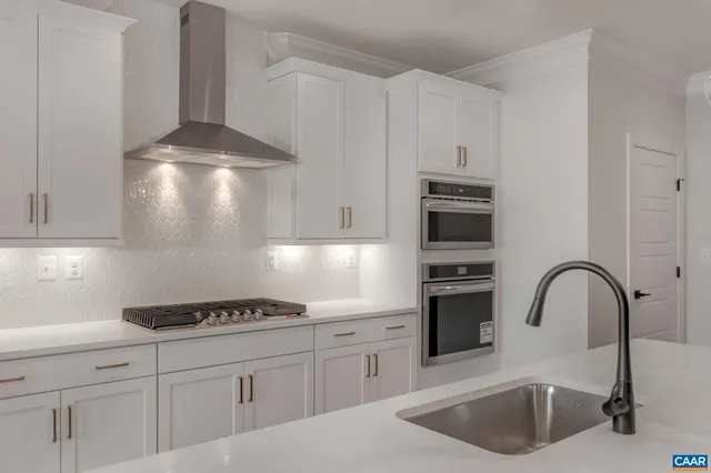 a kitchen with stainless steel appliances granite countertop a sink a stove and refrigerator