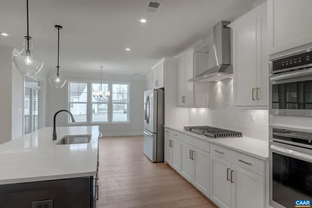 a kitchen with stainless steel appliances a refrigerator a stove and a sink with wooden floor