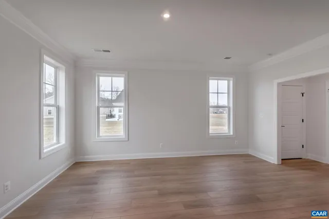 a view of an empty room with wooden floor and window