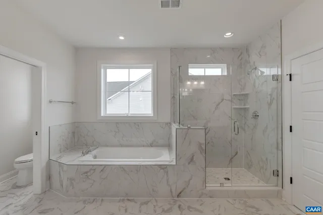 a bathroom with a granite countertop bathtub shower and toilet