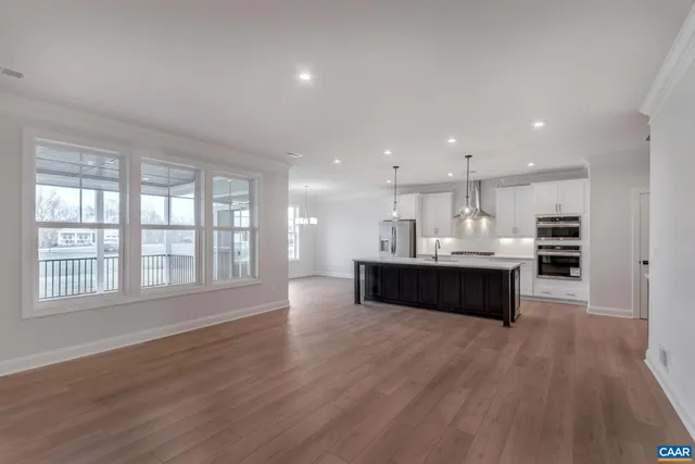 a living room with stainless steel appliances kitchen island wooden cabinets and a couch