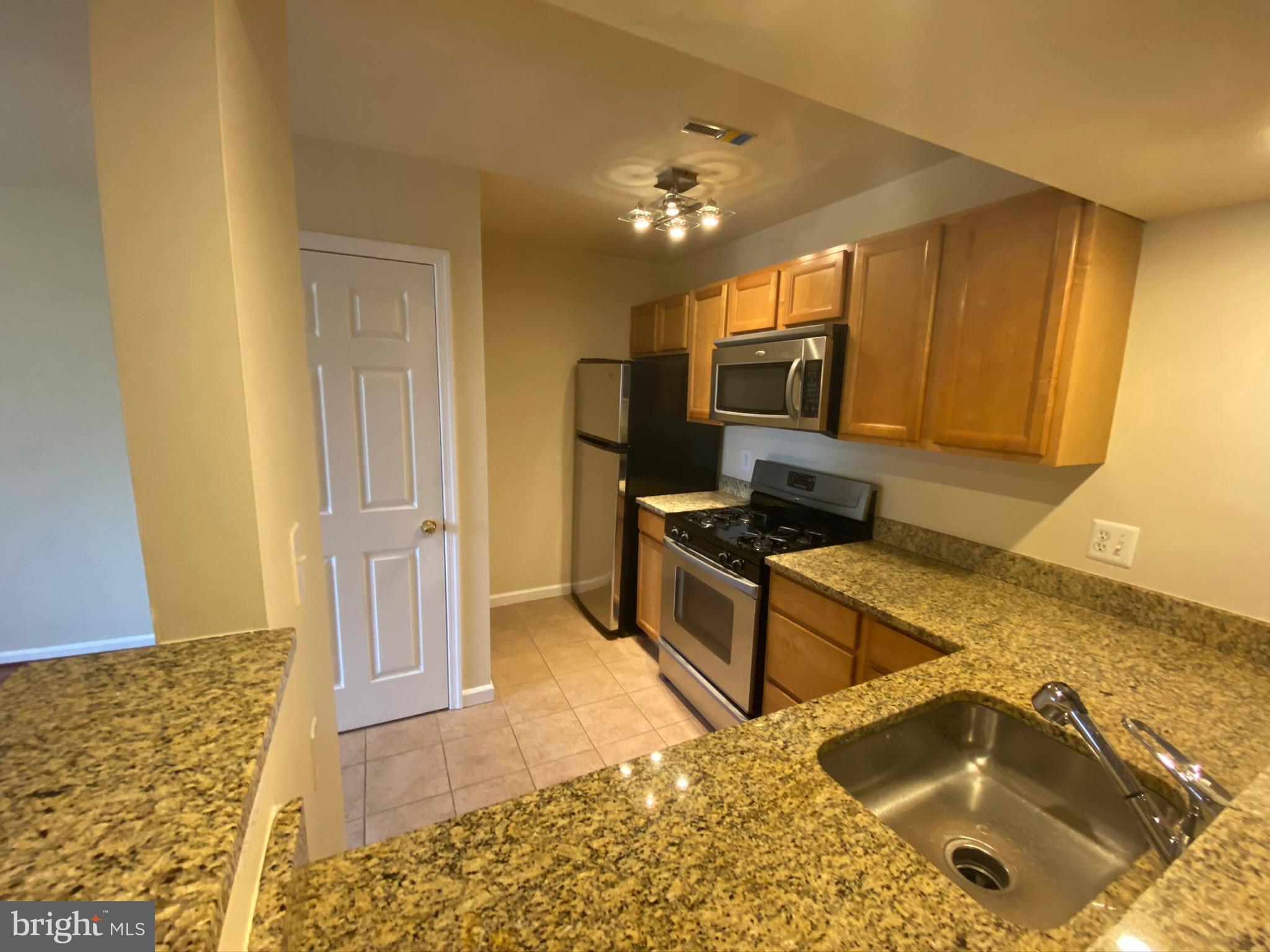 7514 Hawthorne Street, Unit 5 Landover, MD 20785 - Photo 4 of 16 a kitchen with granite countertop a sink and a stove top oven