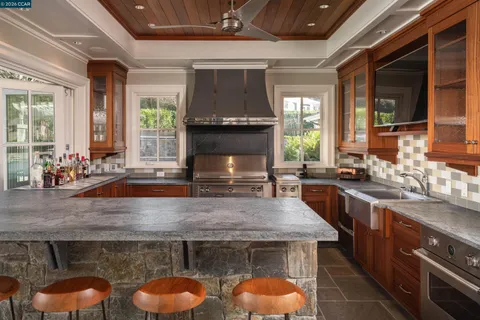a kitchen with granite countertop a stove a sink and a wooden cabinets