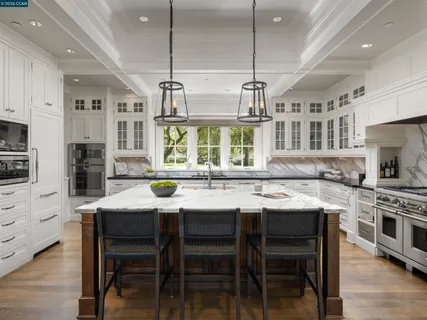 a kitchen with stainless steel appliances granite countertop a stove top oven a sink a dining table and chairs with wooden floor