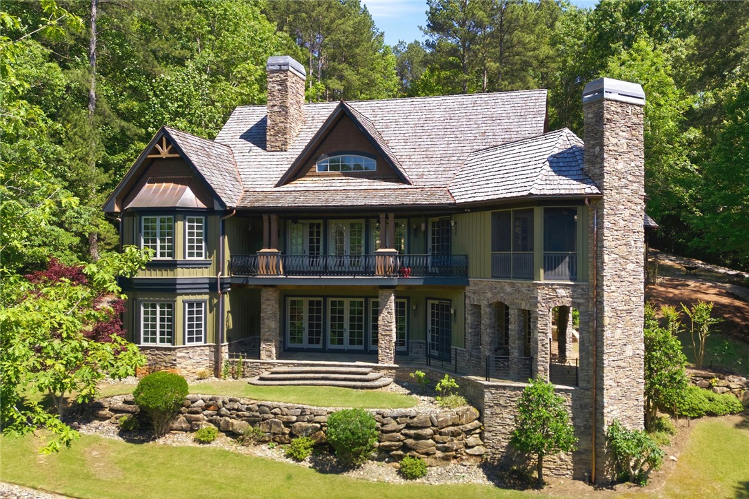 130 River Ridge Road Sunset, SC 29685 - Photo 2 of 47 This charming home is nestled amongst mature trees, featuring a stone chimney and multiple outdoor living spaces.