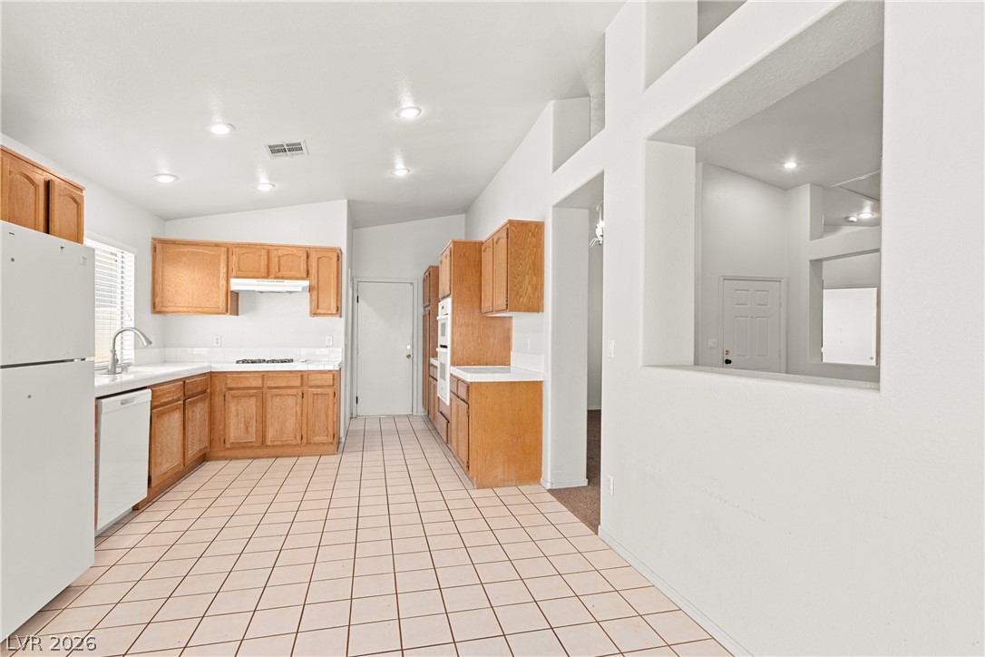 1815 Stablegate Avenue Henderson, NV 89012 - Photo 8 of 28 A well-lit kitchen with natural wood cabinetry and tiled flooring awaits your culinary touch.
