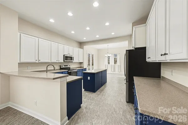 a large kitchen with stainless steel appliances kitchen island granite countertop a refrigerator and a stove top oven