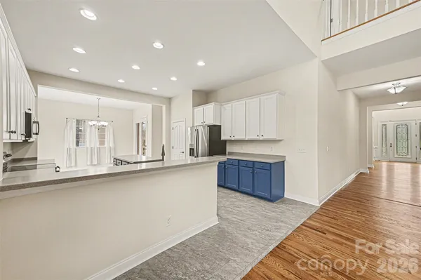 a large kitchen with stainless steel appliances granite countertop a large stove a sink a refrigerator and white cabinets with wooden floor