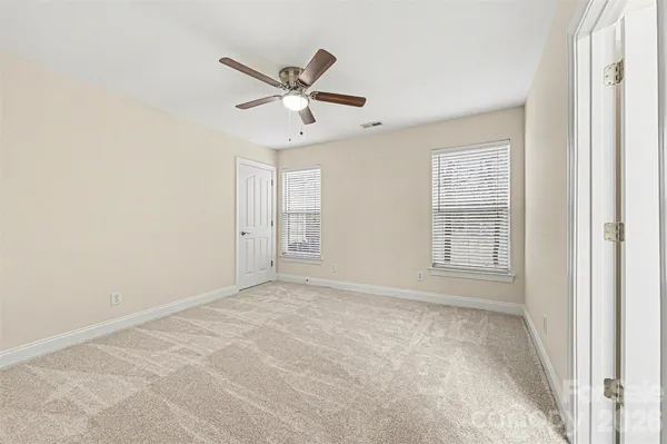 an empty room with windows and fan