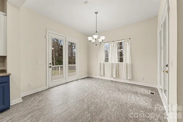 a view of an empty room with chandelier and door