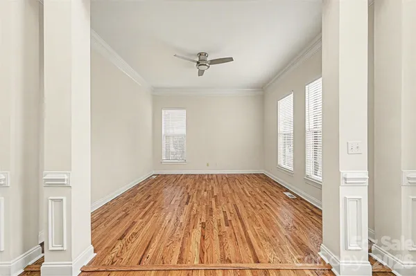 an empty room with wooden floor ceiling fan and windows