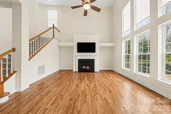 a view of an empty room with wooden floor fireplace and a window