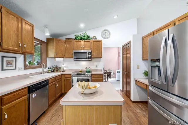 a kitchen with stainless steel appliances granite countertop a sink a stove top oven a refrigerator cabinets and a dining table