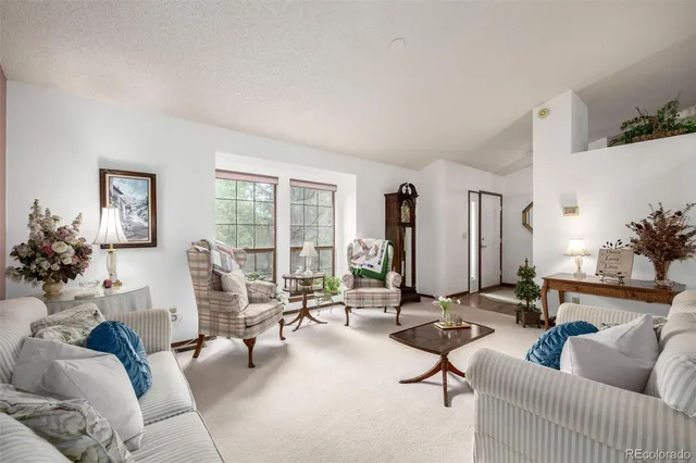 a living room with furniture hard wood floor and a floor to ceiling window